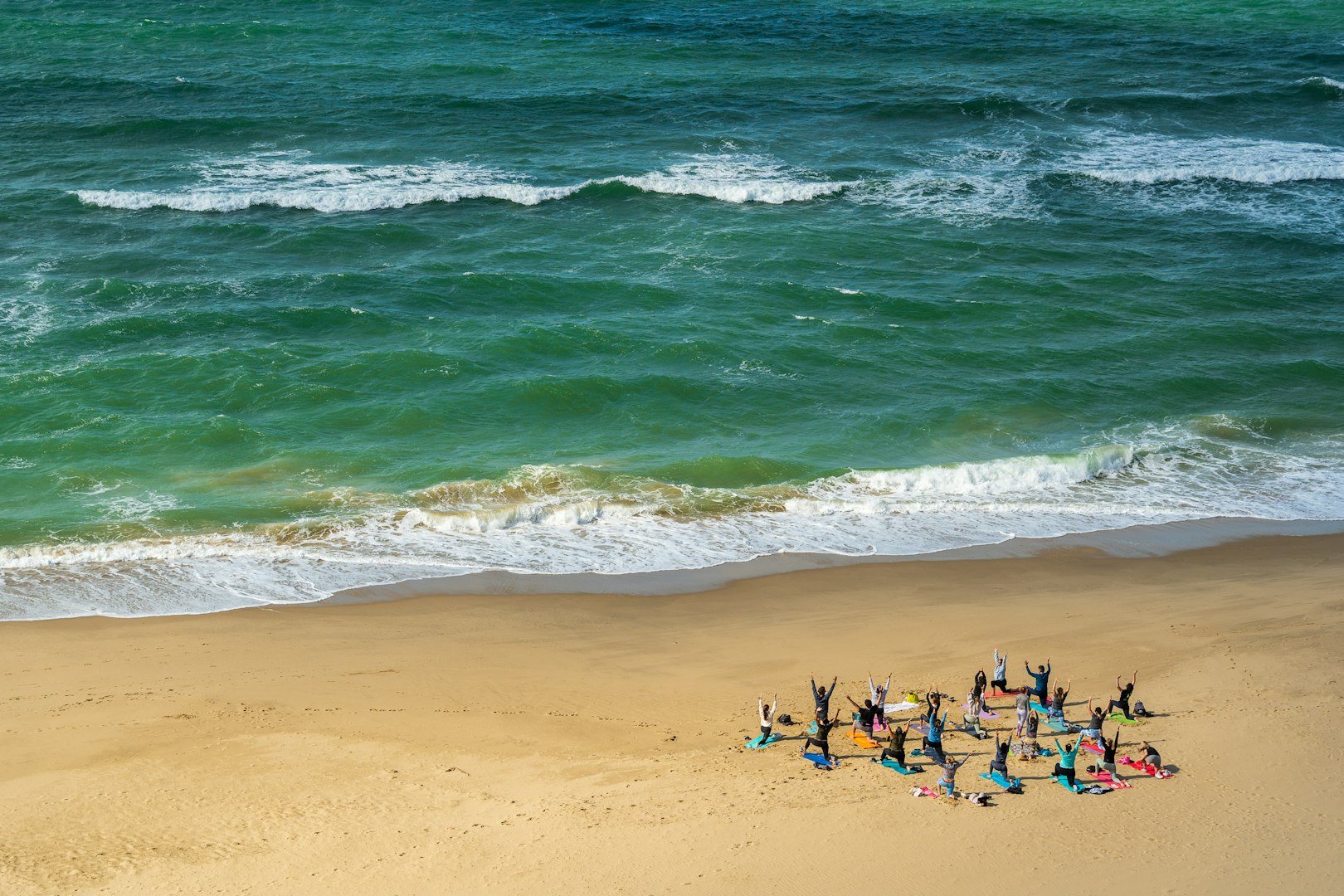 group of people practicing beach yoga